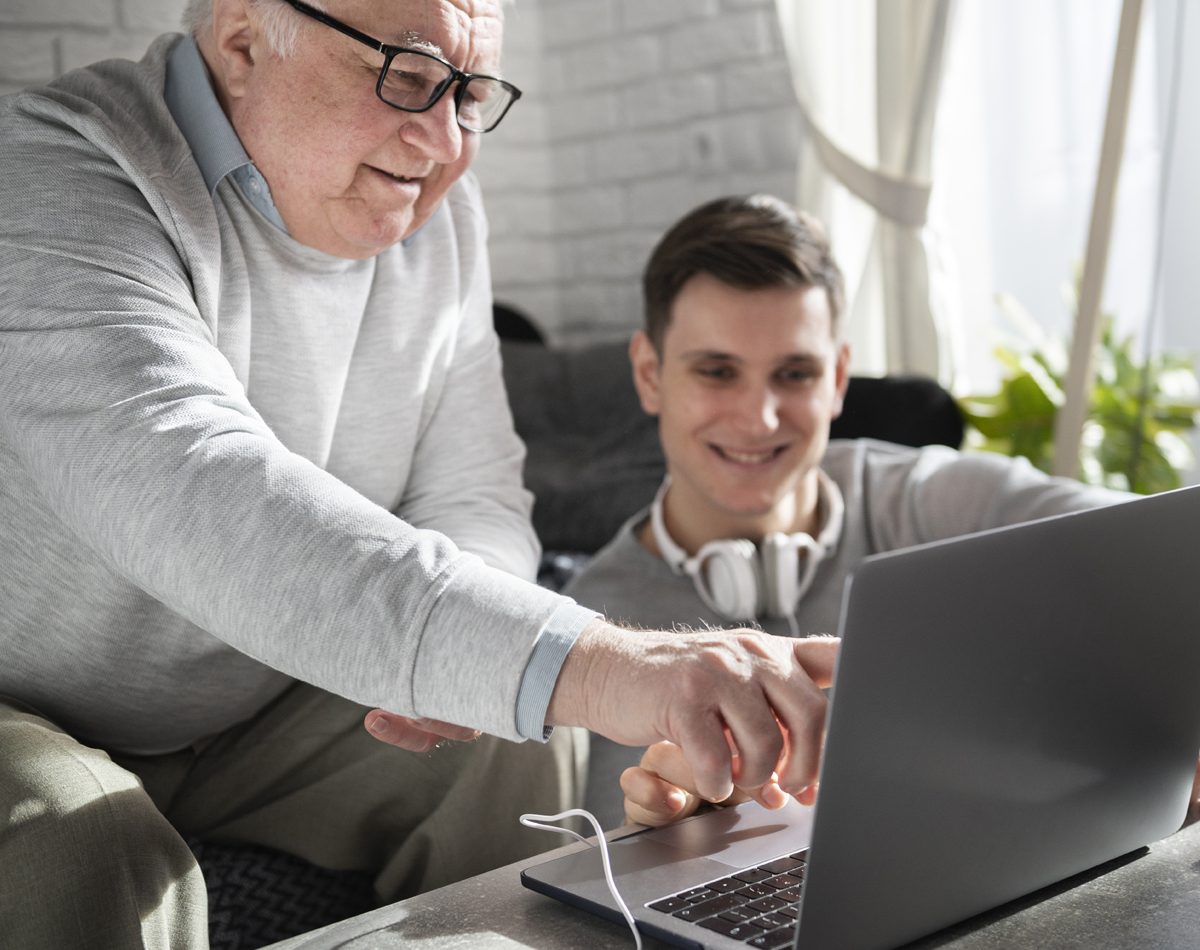 Un proche accompagne calmement une personne dans l’utilisation d’une tablette.