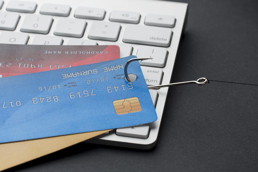 Un hameçon attire des cartes bancaires posées sur un clavier.