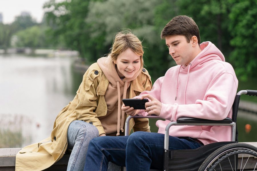 Un proche accompagne calmement une personne avec un appareil numérique.