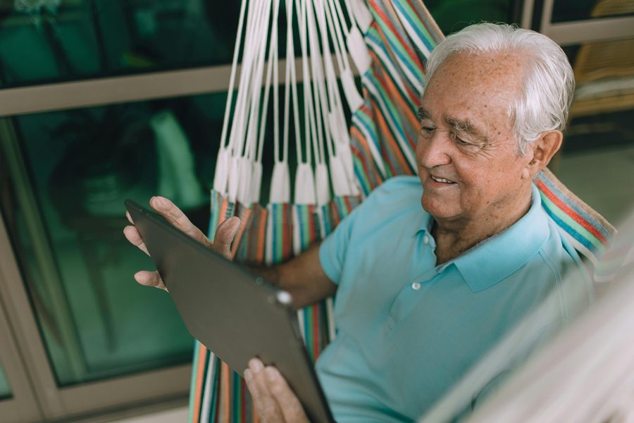 Une personne senior utilise une tablette avec attention.