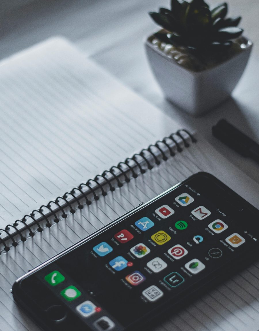 Un carnet, un stylo et un smartphone sont posés sur une table pour préparer un apprentissage numérique.