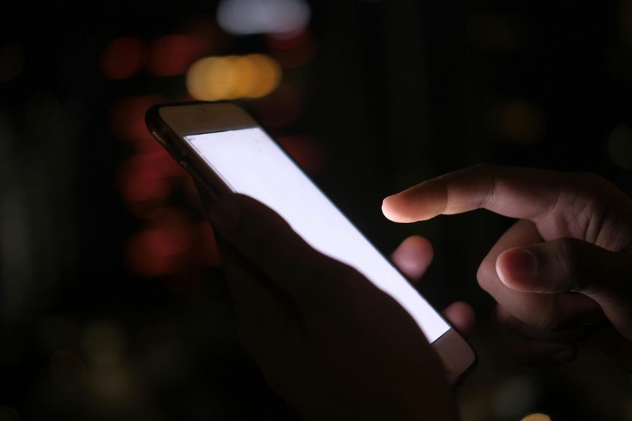 Deux mains utilisent un smartphone sur une table en bois.